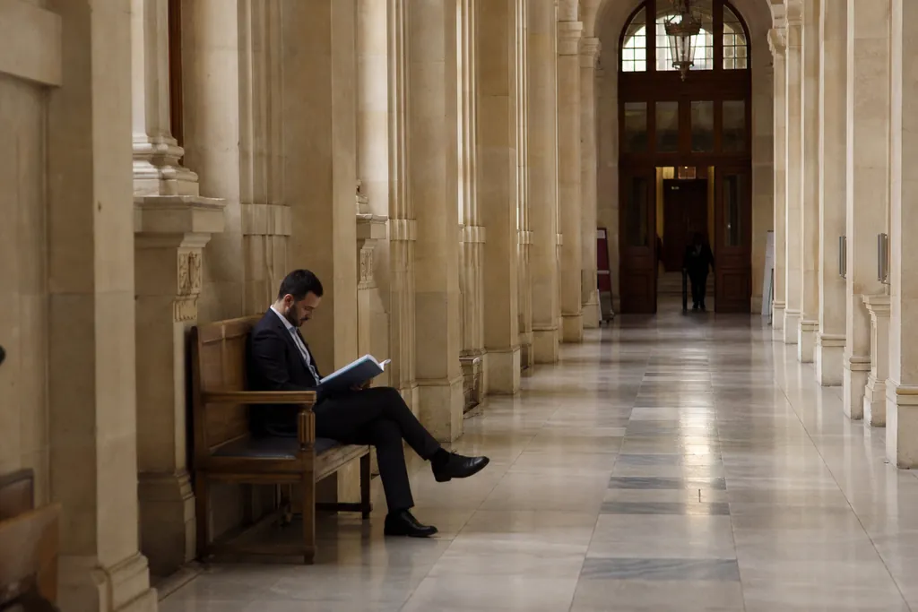 Un homme attend avec un dossier dans le couloir d'un palais de justice